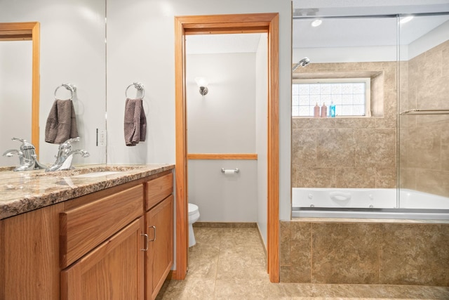 bathroom featuring toilet, tile patterned floors, tiled shower / bath, and vanity