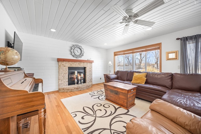 living area featuring light wood-type flooring, wooden ceiling, a fireplace, and ceiling fan