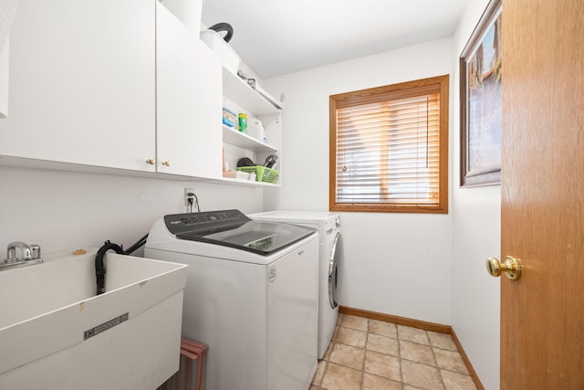 washroom with baseboards, cabinet space, a sink, and washing machine and clothes dryer