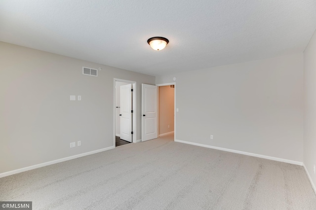 carpeted spare room with visible vents, a textured ceiling, and baseboards