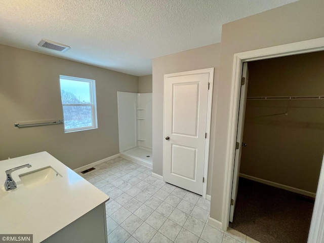 full bath featuring visible vents, a spacious closet, a textured ceiling, and a walk in shower