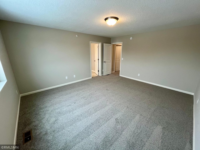 carpeted spare room featuring a textured ceiling and baseboards