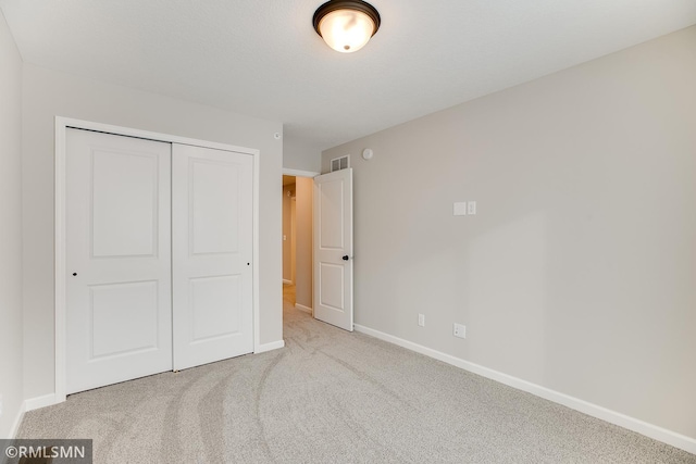 unfurnished bedroom featuring carpet floors, baseboards, visible vents, and a closet