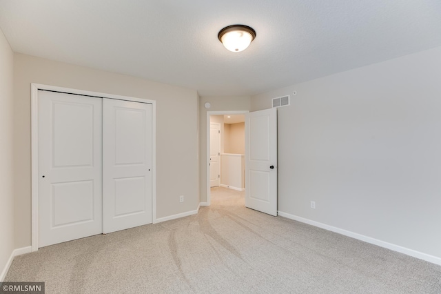 unfurnished bedroom featuring baseboards, visible vents, a closet, and light colored carpet