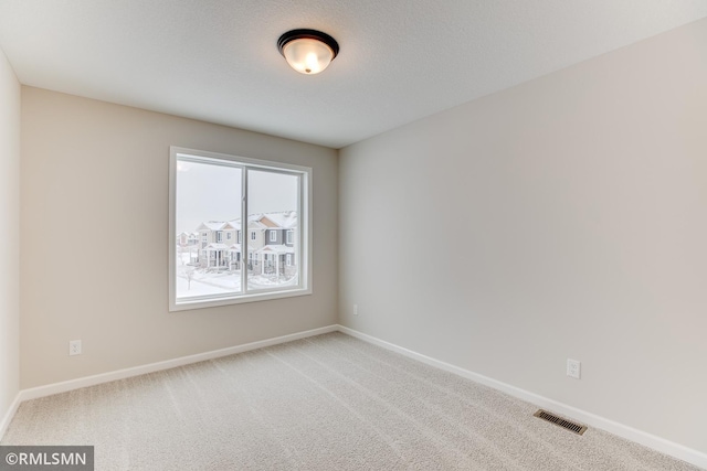 carpeted empty room featuring visible vents, baseboards, and a textured ceiling