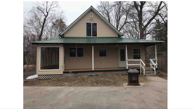 back of house with covered porch and metal roof