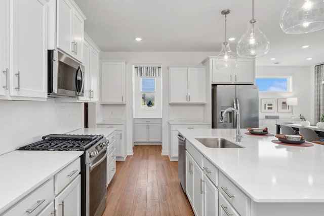 kitchen featuring stainless steel appliances, light countertops, white cabinetry, and a sink