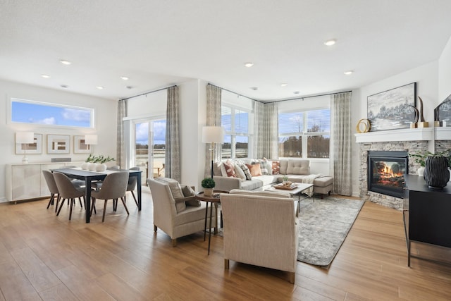 living room featuring recessed lighting, wood finished floors, and a stone fireplace