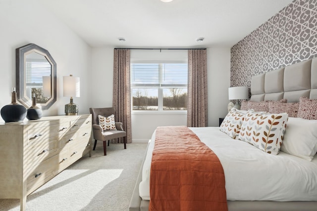 bedroom with an accent wall, light carpet, baseboards, and wallpapered walls