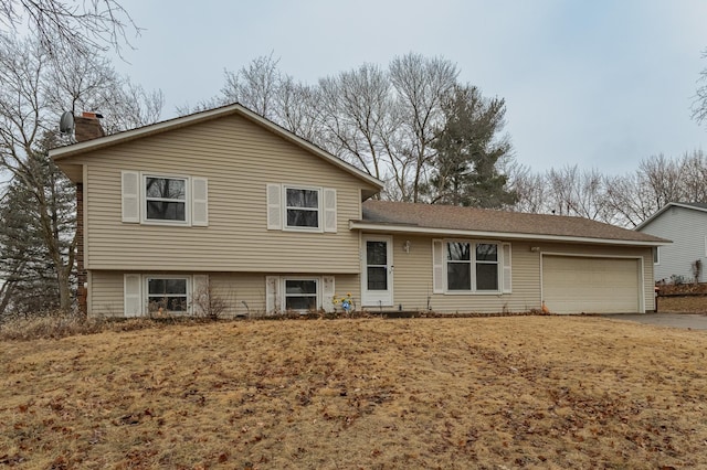 split level home with an attached garage, driveway, and a chimney