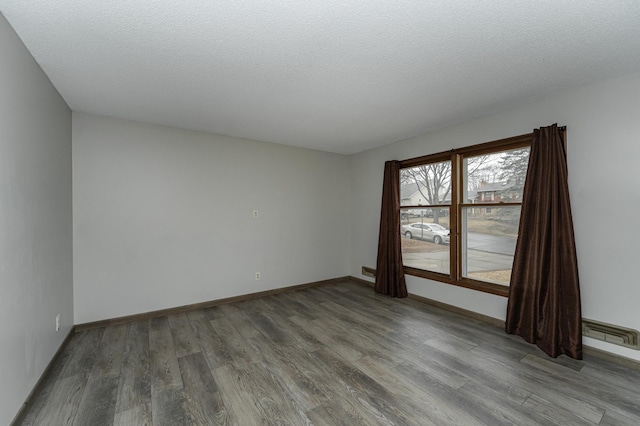 spare room featuring visible vents, a textured ceiling, baseboards, and wood finished floors