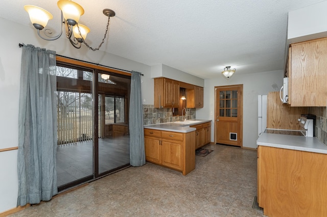 kitchen with brown cabinets, tasteful backsplash, light countertops, white microwave, and a sink