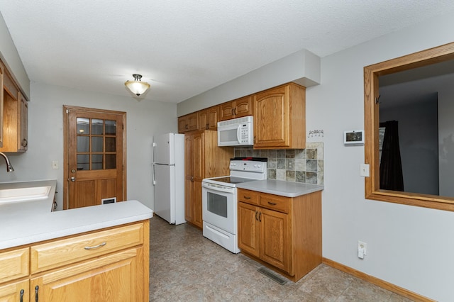 kitchen featuring white appliances, a sink, visible vents, light countertops, and backsplash