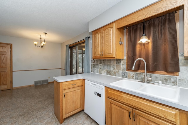 kitchen featuring a peninsula, a sink, visible vents, dishwasher, and tasteful backsplash