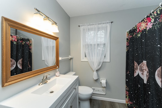 bathroom with a textured ceiling, toilet, wood finished floors, vanity, and baseboards