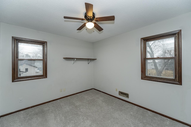 carpeted empty room with ceiling fan, a textured ceiling, and baseboards