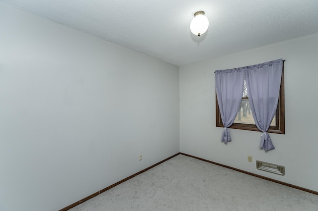 unfurnished room with baseboards, a textured ceiling, and light colored carpet