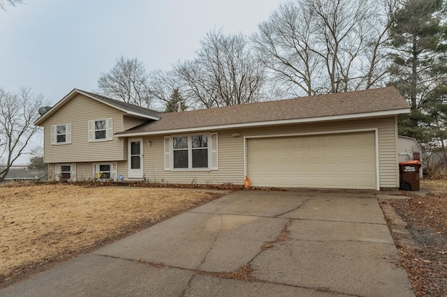 tri-level home featuring a garage, driveway, and roof with shingles