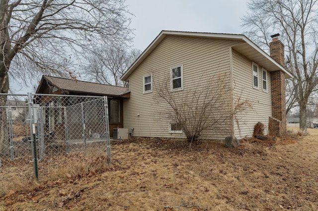 back of property with central AC, fence, and a chimney