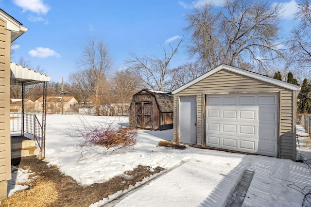 snow covered garage featuring a garage and fence