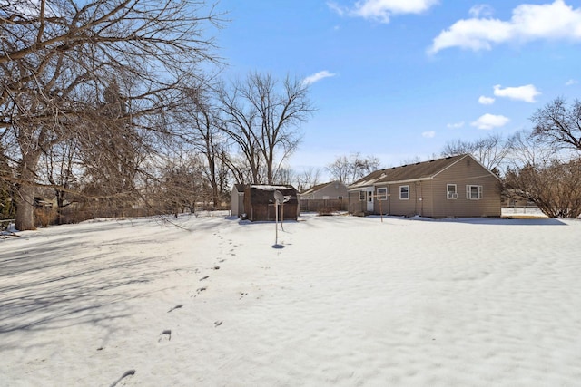 yard layered in snow with a storage unit, an outdoor structure, and fence