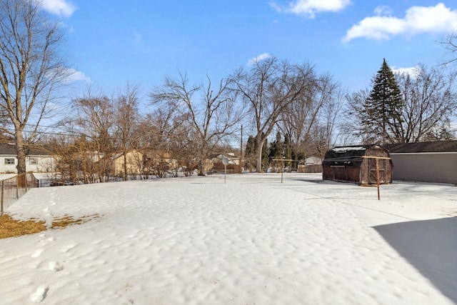 snowy yard with an outdoor structure, fence, and a shed