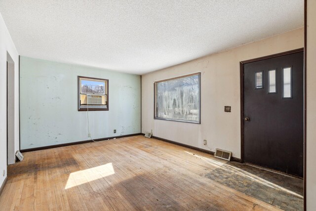 foyer with hardwood / wood-style floors, cooling unit, baseboards, and visible vents