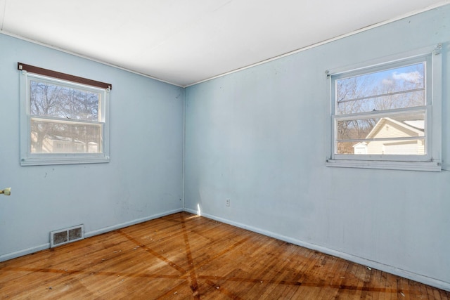 empty room featuring visible vents, baseboards, and wood-type flooring