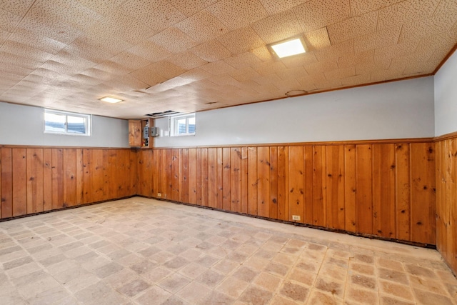 below grade area featuring tile patterned floors, a wainscoted wall, and wood walls