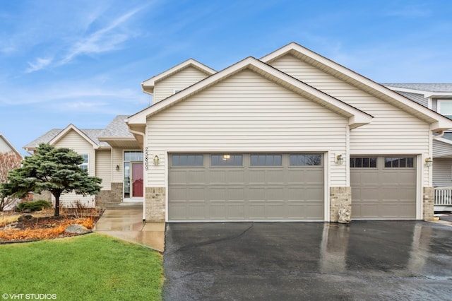 view of front of house featuring a garage, stone siding, and driveway