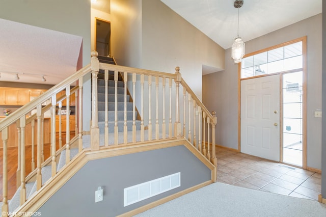 entrance foyer featuring track lighting, stairway, visible vents, and tile patterned floors