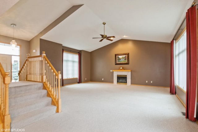 living room featuring light carpet, baseboards, lofted ceiling, stairway, and a fireplace