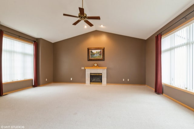 unfurnished living room with plenty of natural light, vaulted ceiling, a tiled fireplace, and baseboards