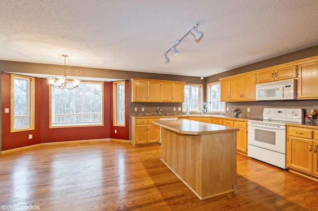 kitchen featuring pendant lighting, light wood finished floors, a kitchen island, a textured ceiling, and white appliances