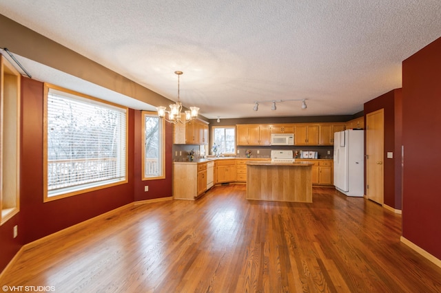 kitchen featuring dark wood-style floors, light countertops, a textured ceiling, a chandelier, and white appliances