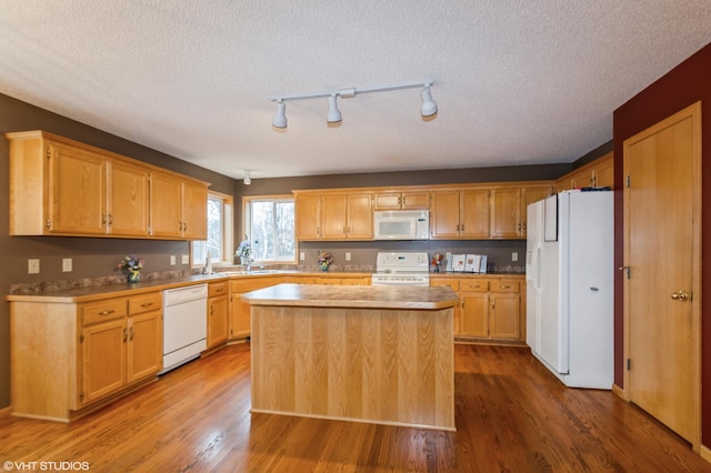 kitchen with white appliances, a kitchen island, dark wood-type flooring, and a textured ceiling