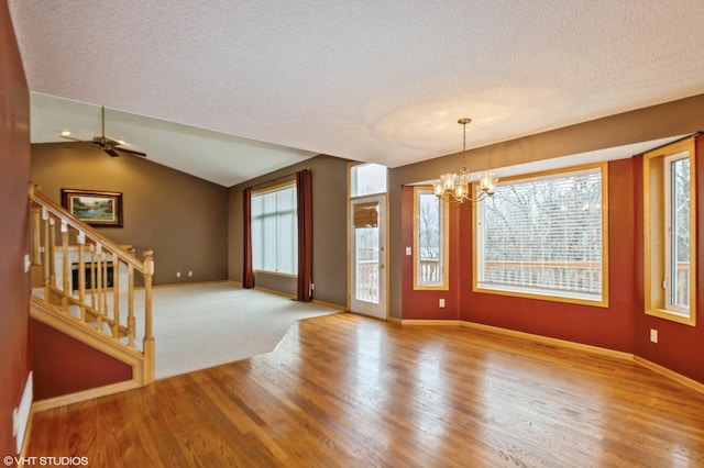 spare room featuring plenty of natural light, stairway, vaulted ceiling, and a textured ceiling