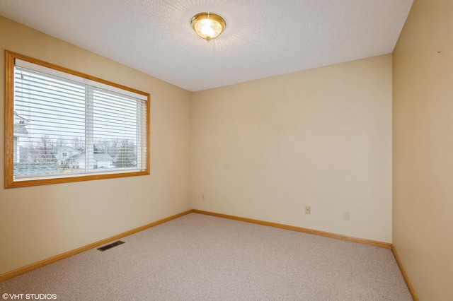 carpeted spare room with visible vents, a textured ceiling, and baseboards