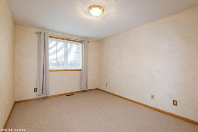 carpeted empty room with baseboards, visible vents, and a textured ceiling