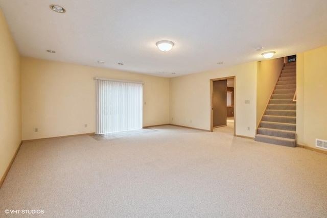 spare room featuring visible vents, light carpet, stairway, and baseboards