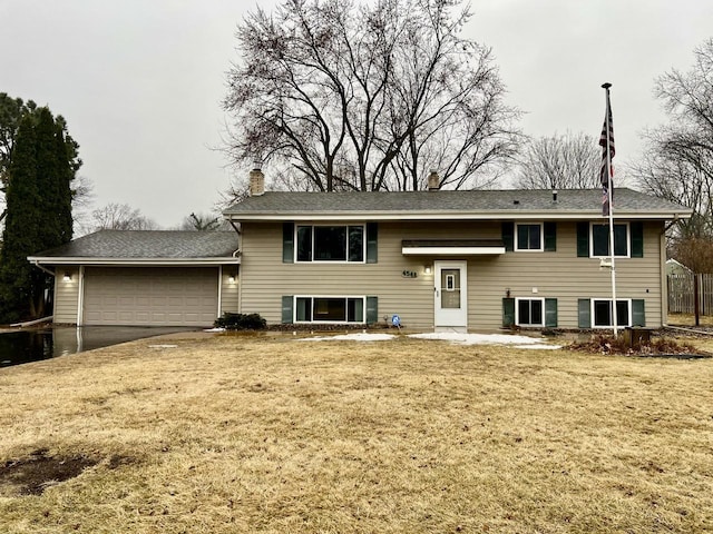 bi-level home featuring a front yard, a chimney, and an attached garage