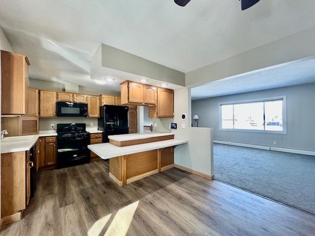 kitchen featuring baseboards, light countertops, a peninsula, and black appliances