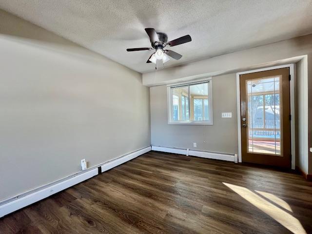 unfurnished room featuring a baseboard radiator, dark wood-style flooring, a textured ceiling, and baseboards