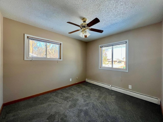 spare room with plenty of natural light, a baseboard heating unit, dark carpet, and baseboards