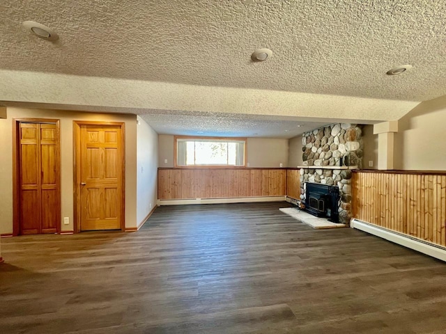 unfurnished living room featuring dark wood finished floors, wainscoting, a baseboard radiator, baseboard heating, and a textured ceiling