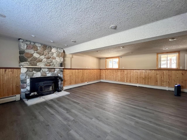 unfurnished living room featuring a wealth of natural light, wainscoting, a textured ceiling, and wood finished floors