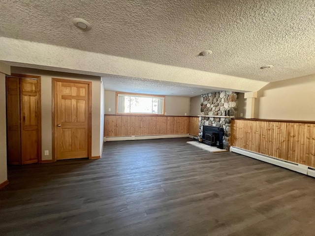 basement featuring a wainscoted wall, dark wood-type flooring, a textured ceiling, and a baseboard radiator