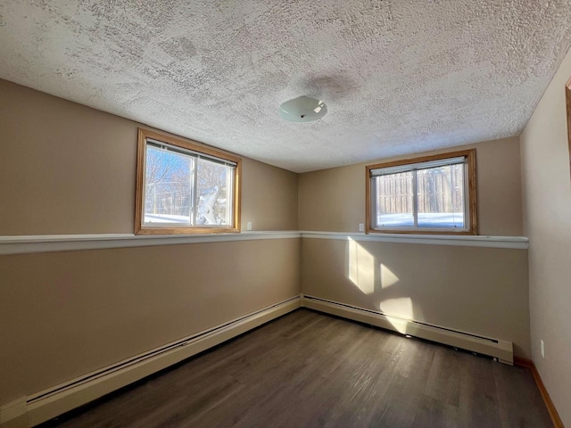 spare room with a baseboard radiator, a textured ceiling, baseboards, and wood finished floors