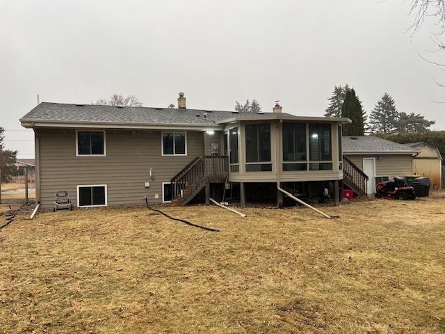 rear view of property with an outbuilding, a sunroom, stairs, a yard, and a shed