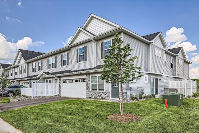 view of front of home with driveway, a garage, fence, and a front lawn